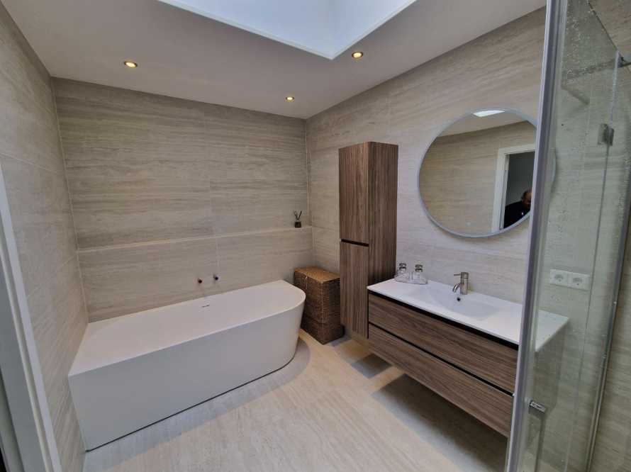 Luxe badkamer met vrijstaand bad, ronde spiegel en houtlook meubel