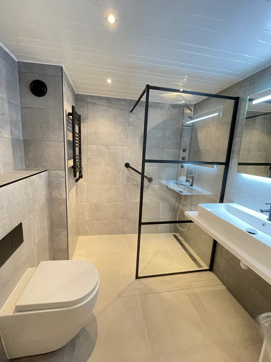 Badkamer met zwarte glaswand, hangtoilet en zwevend wastafelmeubel