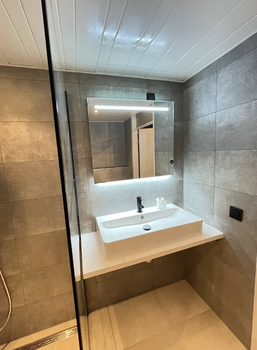 Compacte badkamer met verlichte spiegel en wit wastafelblad